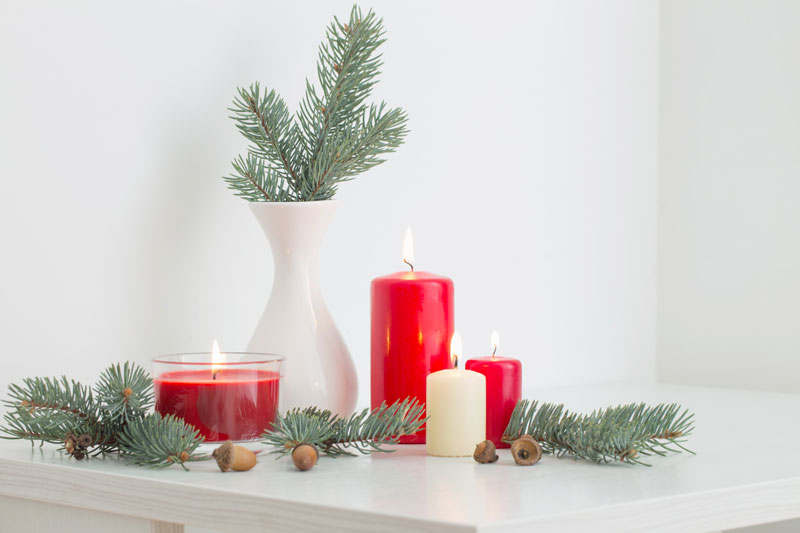 Déco noel DIY avec bougies rouges et branches de sapin dans un vase blanc.