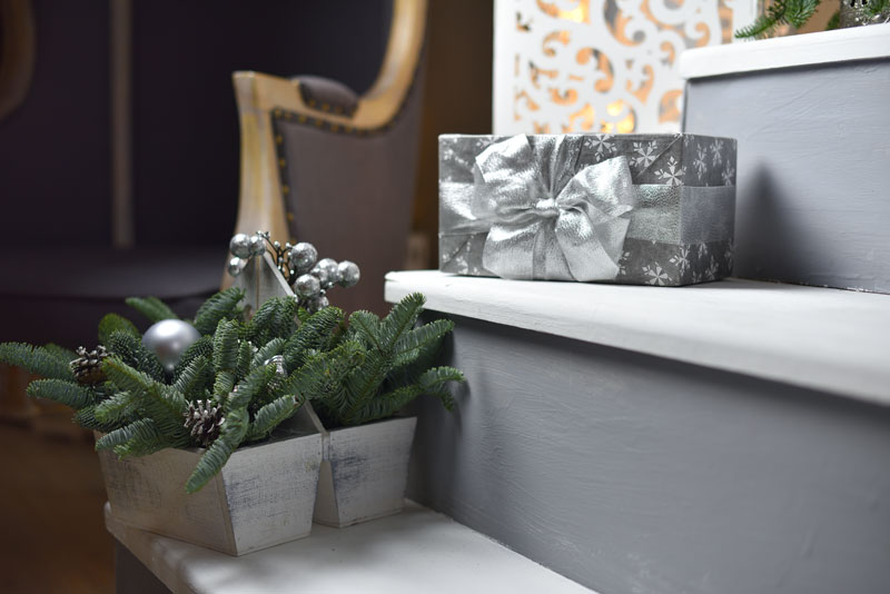 Pots décorés avec branches de sapin, pommes de pin et boules de Noël argentées.