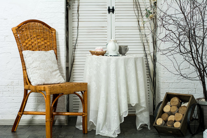 petit salon shabby avec chaise marron en osier et coussins blancs brodés