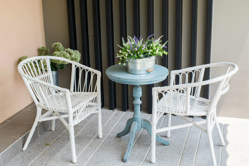 terrasse décorée en style shabby chic avec deux chaises en osier et une petite table