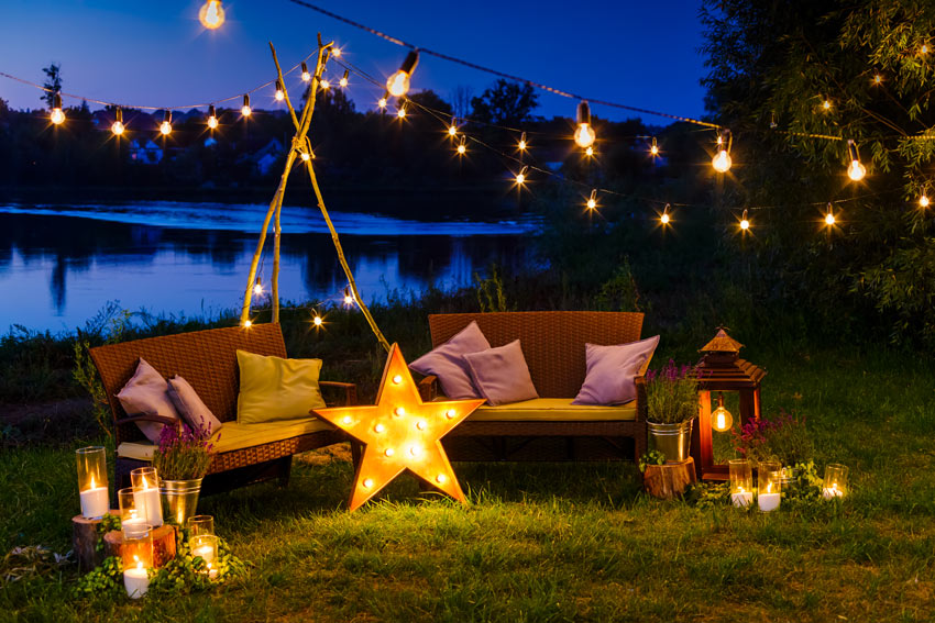 jardin illuminé avec lampes en forme d'étoile et ampoules suspendues à un fil