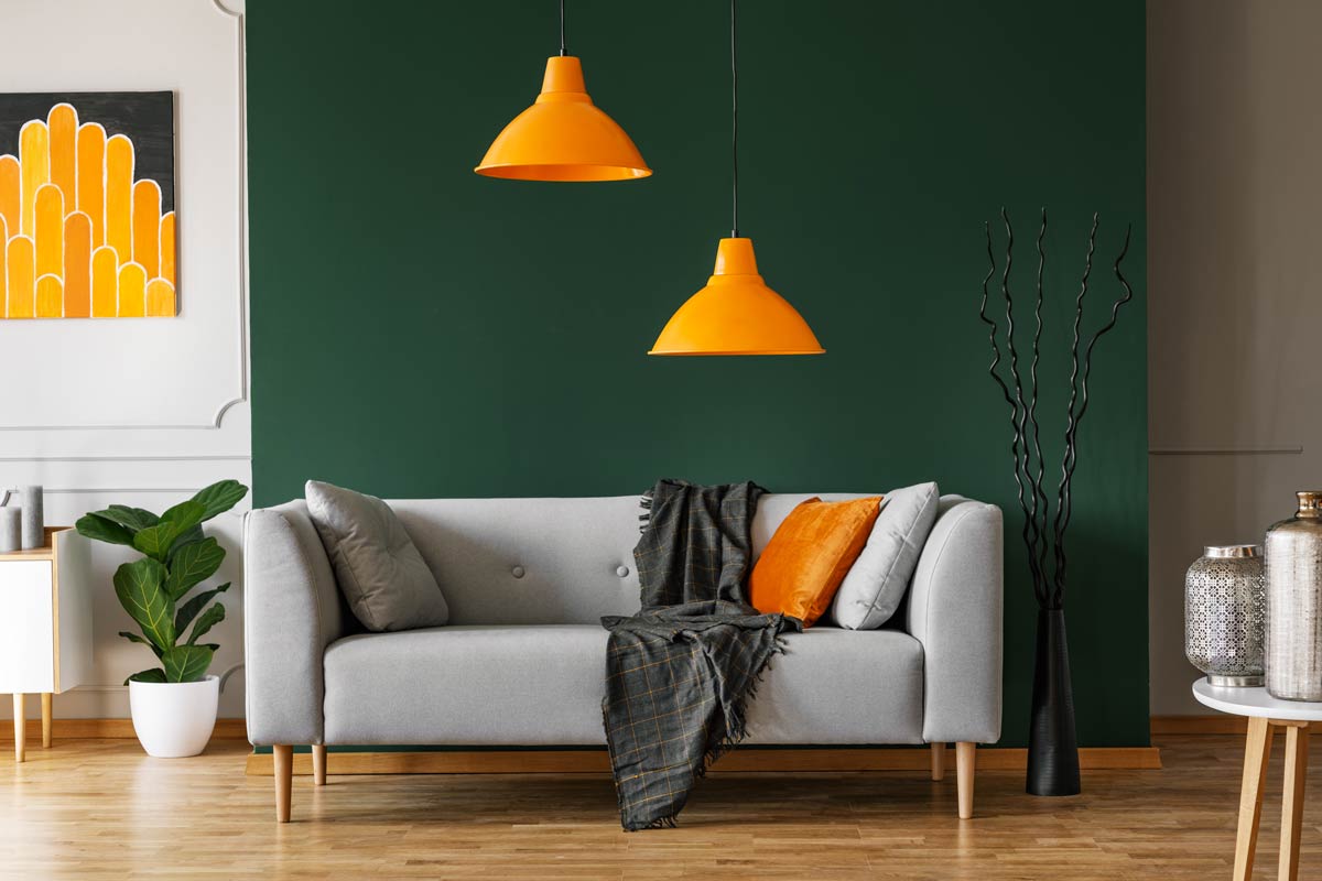 salon avec mur vert bouteille et lampadaires design orange.