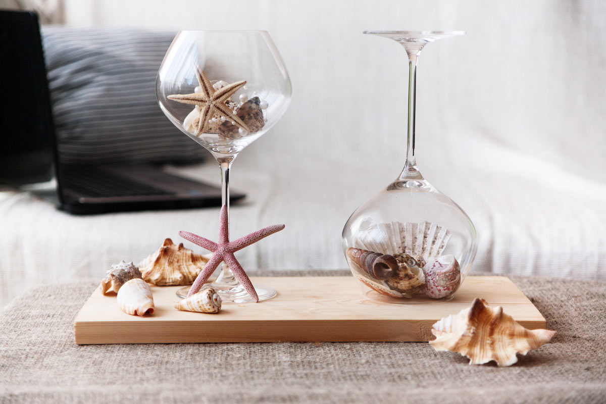 Centre de table avec des verres recyclés et des coquillages.