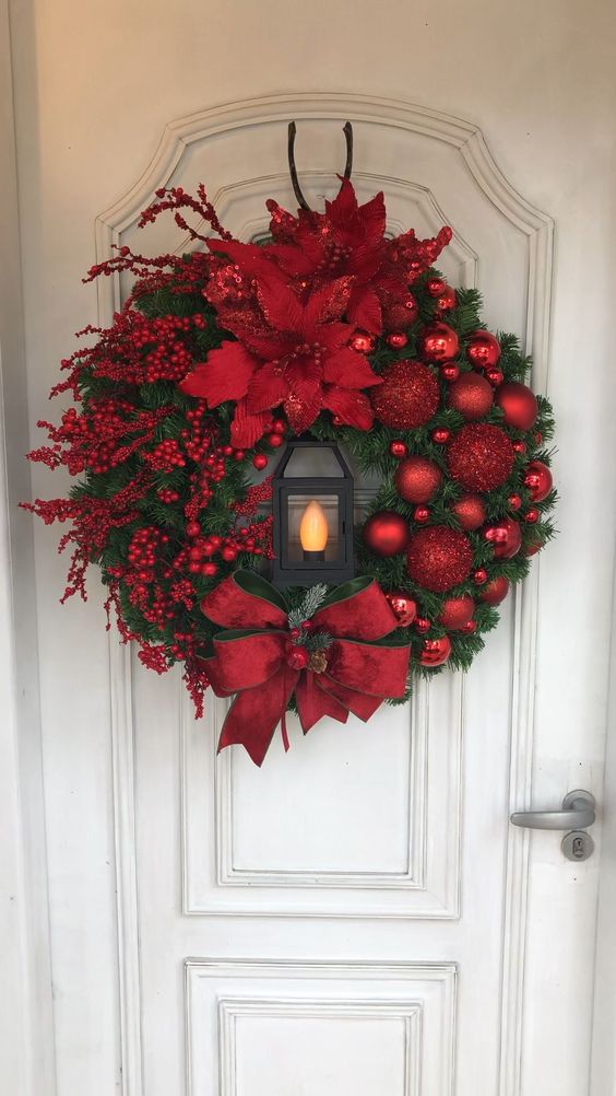 Ghirlanda rossa con lanterna per decorare la porta d'ingresso a natale.