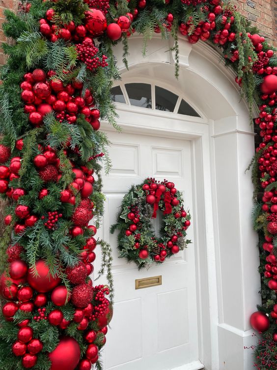 Bellissima decorazione di un portone per natale con ghirlanda di pino e palline rosse.