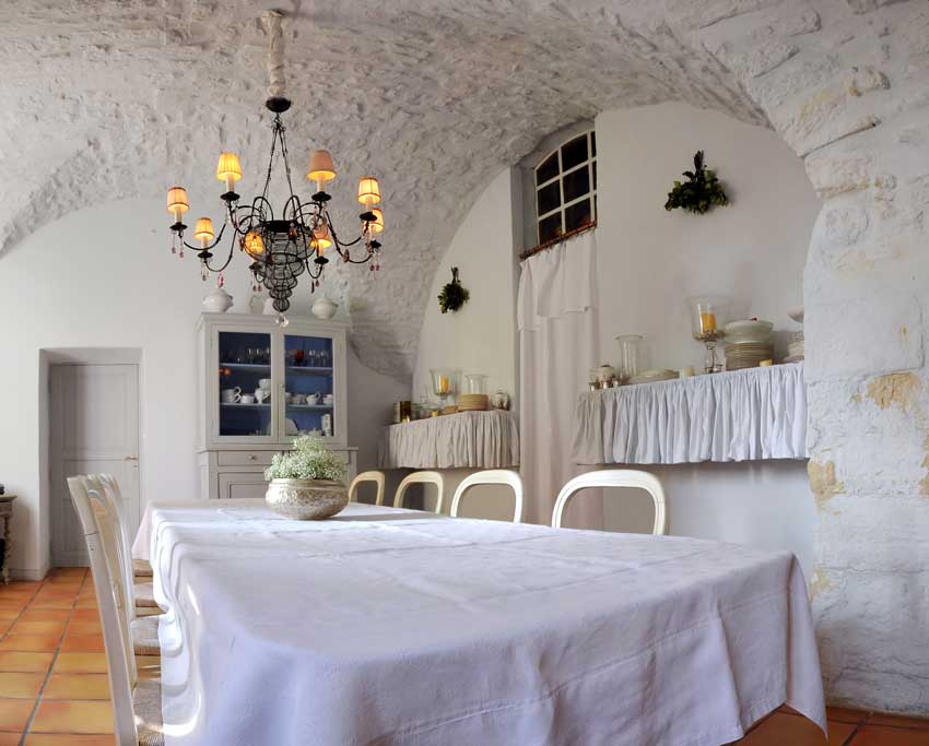Salle à manger typiquement provençale, beaux rideaux blancs et lustre en bois.
