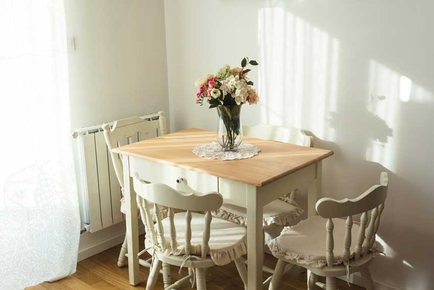 Petite salle à manger au décor shabby chic, table avec plateau en bois et vase central.