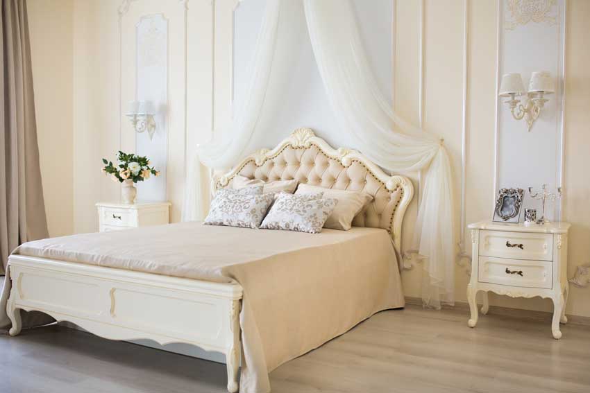 chambre à coucher de style shabby avec rideaux transparents au-dessus du lit, belle table de chevet blanche.