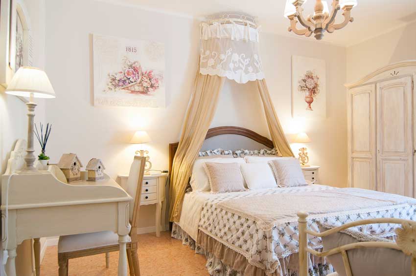 chambre au décor shabby chic, lit avec rideaux beiges.