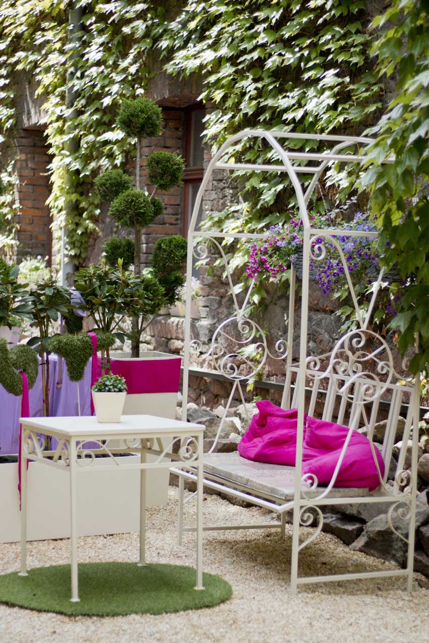 jardin meublé dans un style shabby chic, table basse en fer forgé blanc.