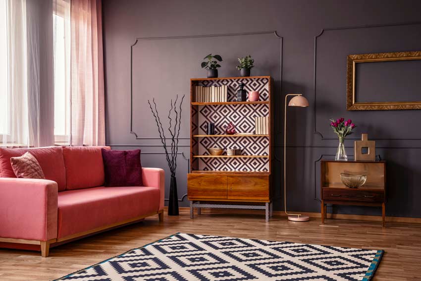 salon avec mur gris et divan rose et style retrò