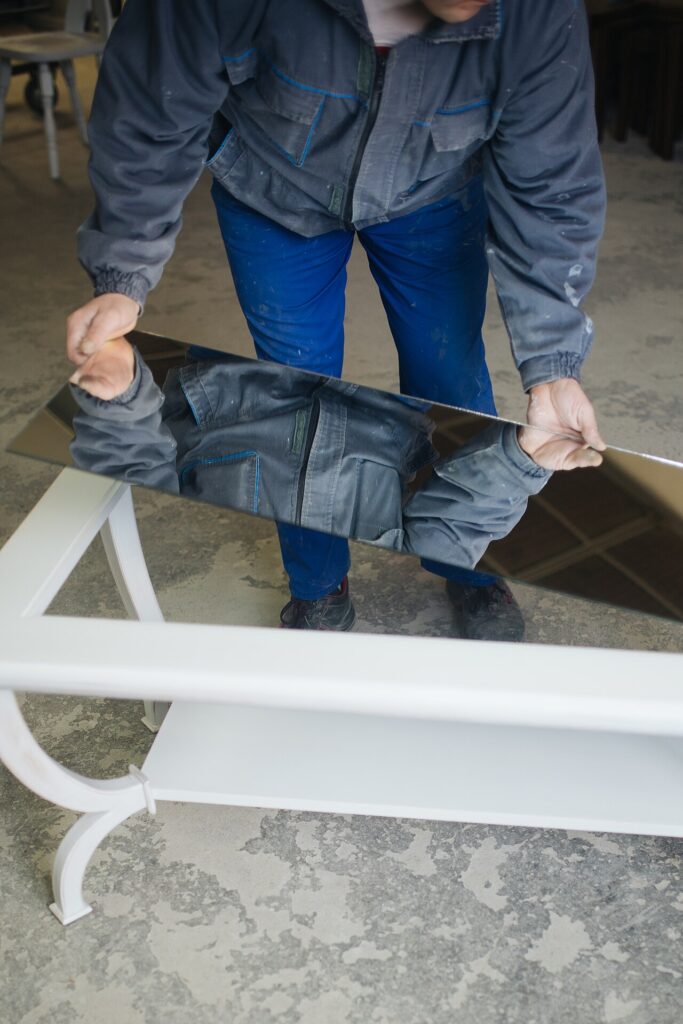 Voici 7 façons d’ agrandir une pièce avec un miroir! Laissez - Close-up of a carpenter putting a mirror in the middle of an unfinished table